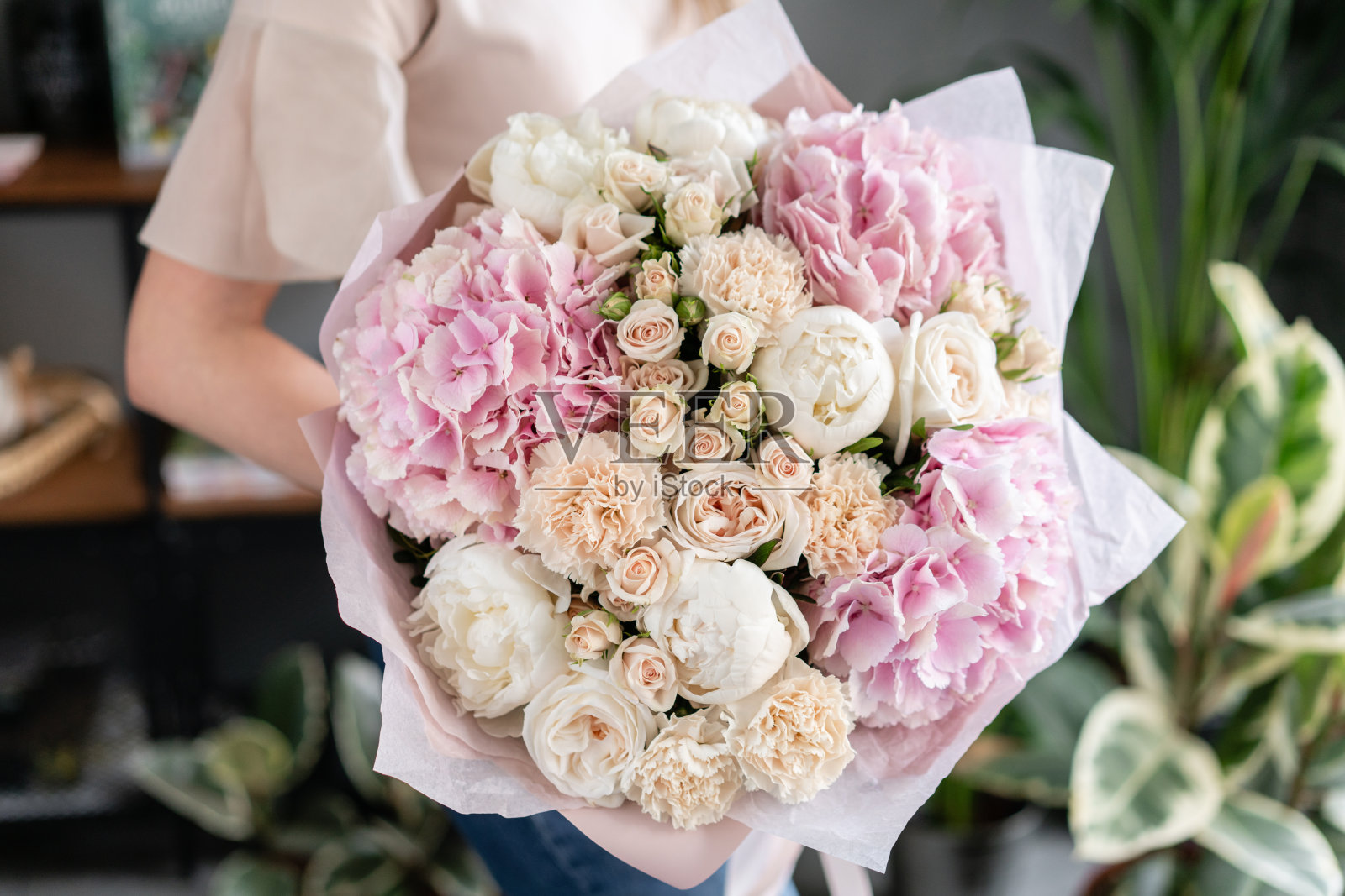 白色的牡丹和粉色的绣球花。女人手里拿着一束美丽的混合鲜花。花店概念。英俊的新鲜的花束。花交付。红色和粉红色。照片摄影图片