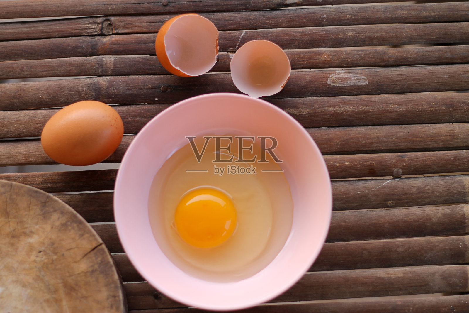蛋壳与鸡蛋和打开鸡蛋在一个粉红色的碗放置在肉铺附近的竹条上。顶视图的特写镜头。照片摄影图片