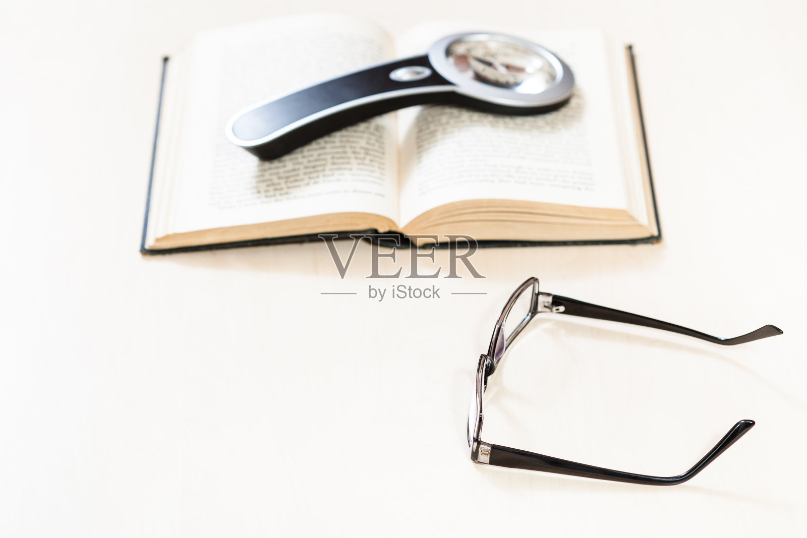 眼镜和放大镜放在打开的书上照片摄影图片
