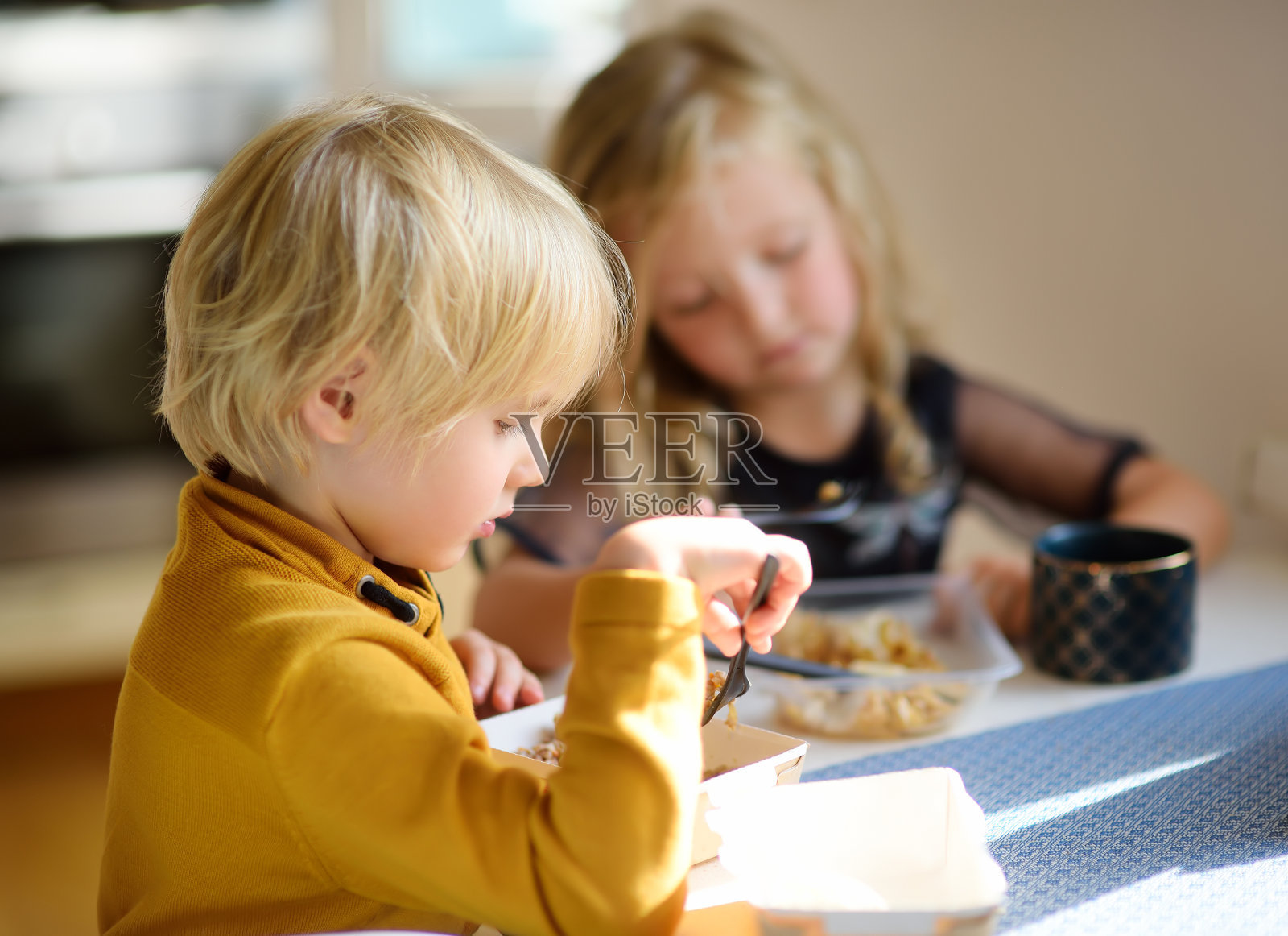 学龄前儿童在家里的厨房里吃快餐或方便食品。大城市现代家庭的营养。食品外卖服务。照片摄影图片