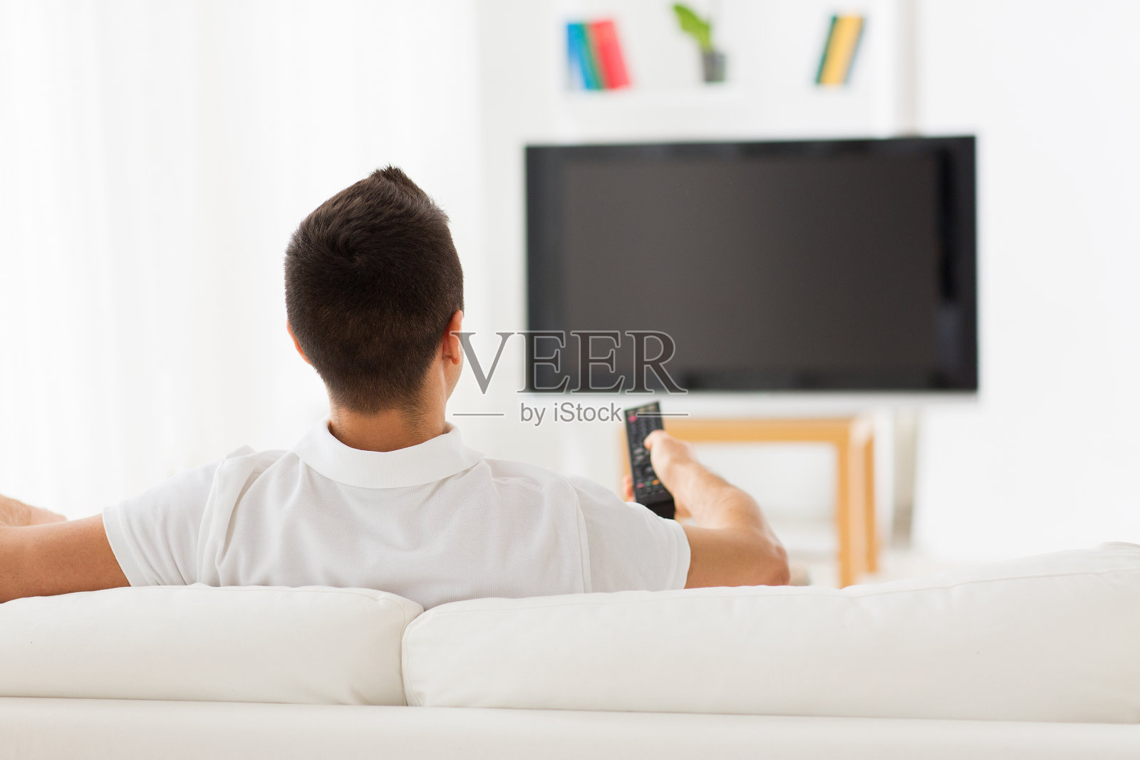 男人在家里看电视，换频道照片摄影图片