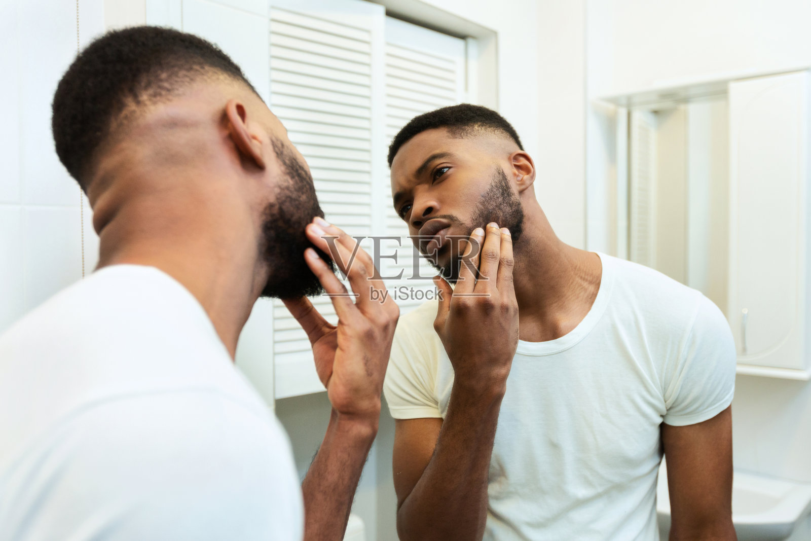一个焦虑的非洲男人在浴室里看着镜子照片摄影图片