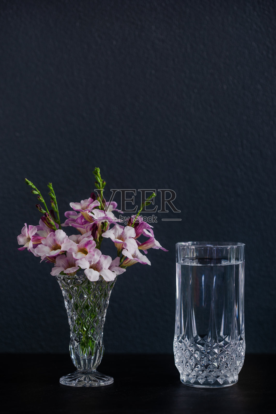 桌上的花瓶里放着一杯水和几朵紫色的花照片摄影图片