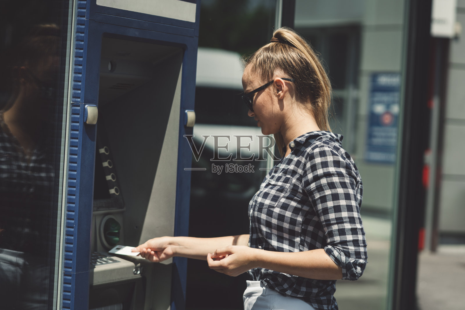 一个用非接触式银行卡在自动取款机上取款的女人照片摄影图片