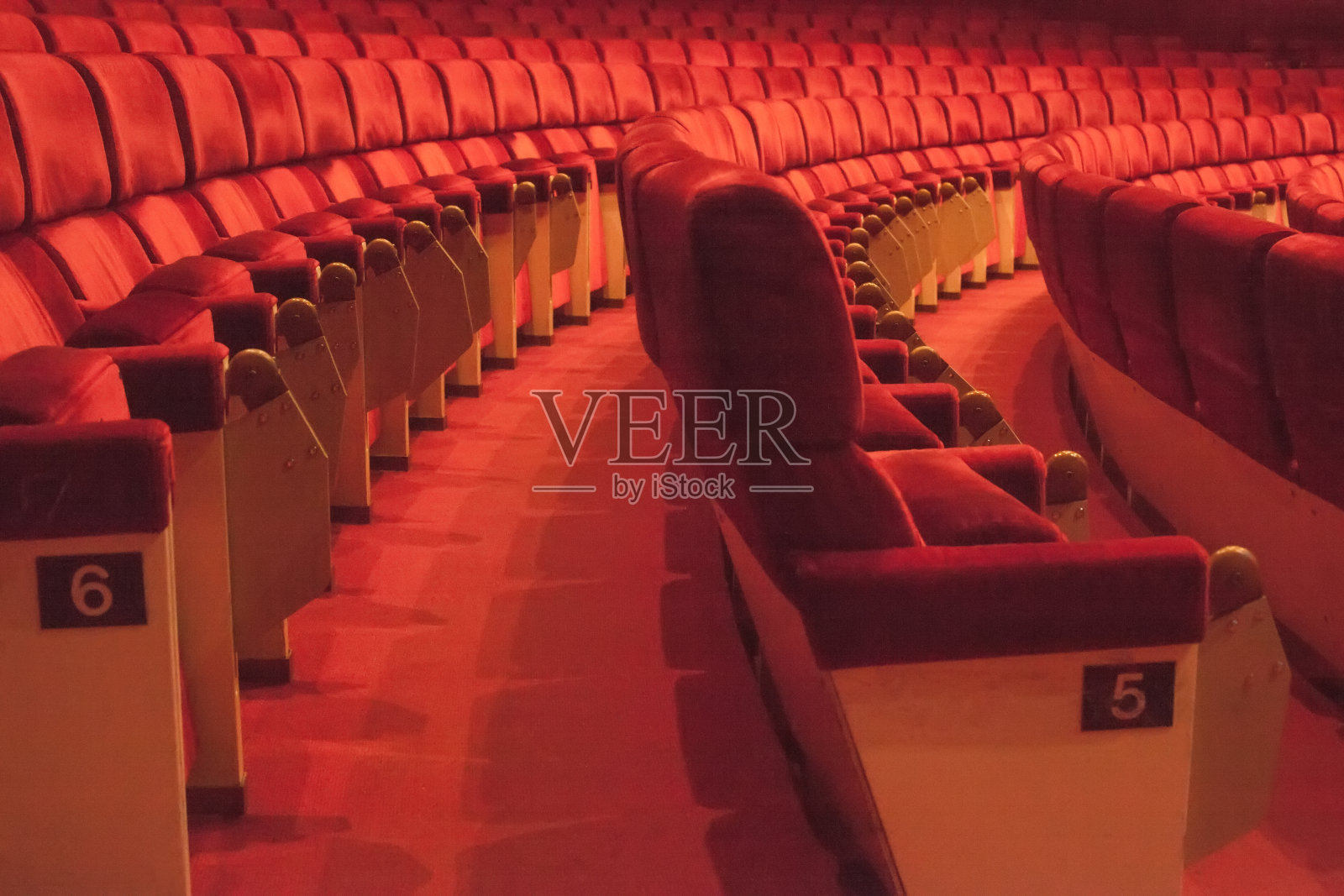 一排排标有数字的红色电影院座位。空荡荡的剧院大厅。舒适的椅子在现代剧院内部照片摄影图片