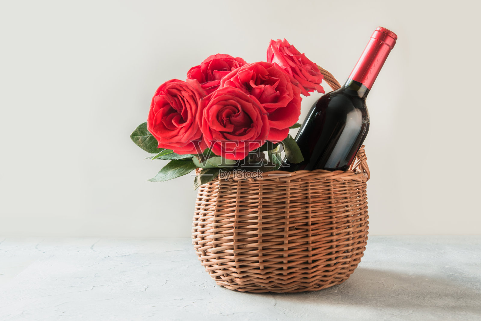 礼物篮，一束红玫瑰，一瓶白葡萄酒。照片摄影图片