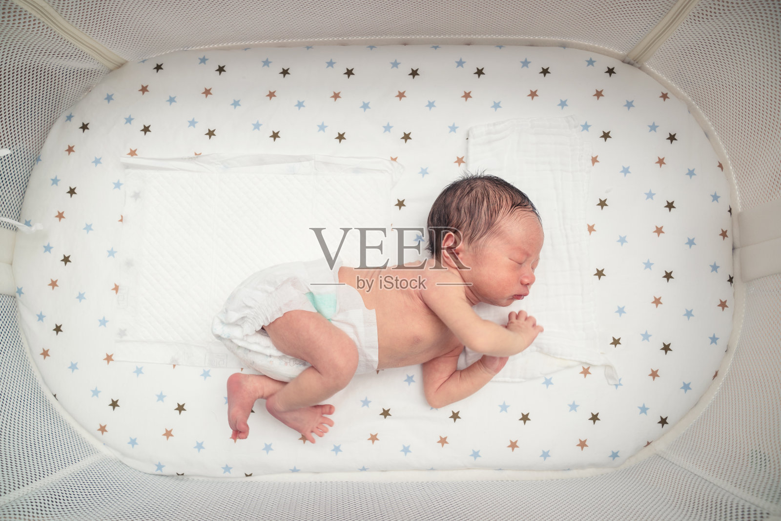 在婴儿床里熟睡的新生婴儿照片摄影图片