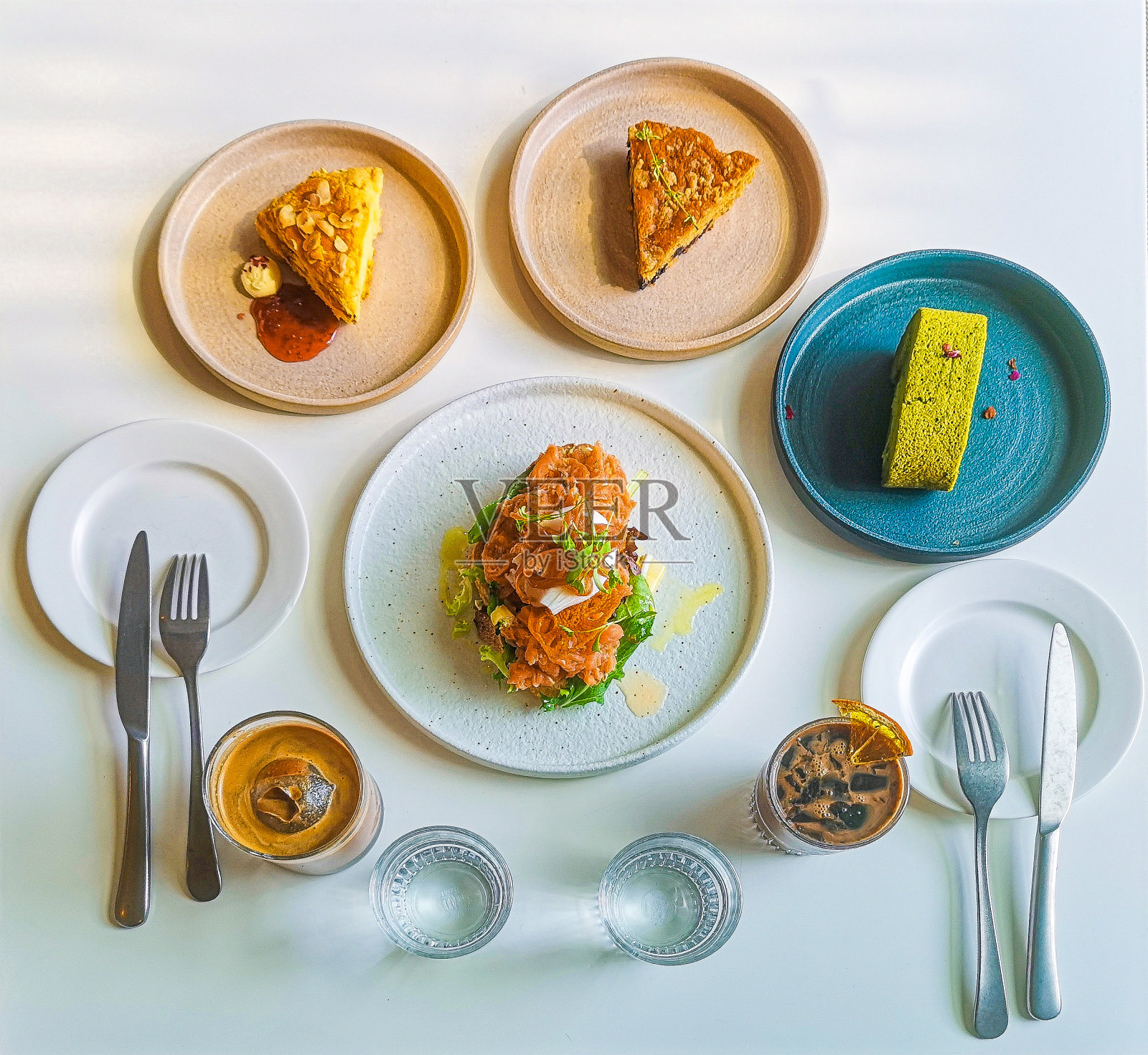 日式和西方融合的食物(鲑鱼和鳄梨吐司，果酱和凝固奶油的司康饼，胡萝卜蛋糕，Macha雪风蛋糕，冰咖啡，几杯水)照片摄影图片