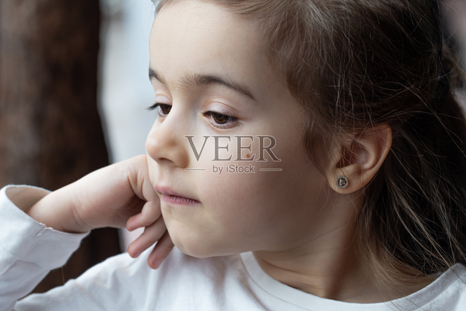一个美丽的小女孩沉思着看着窗外。照片摄影图片