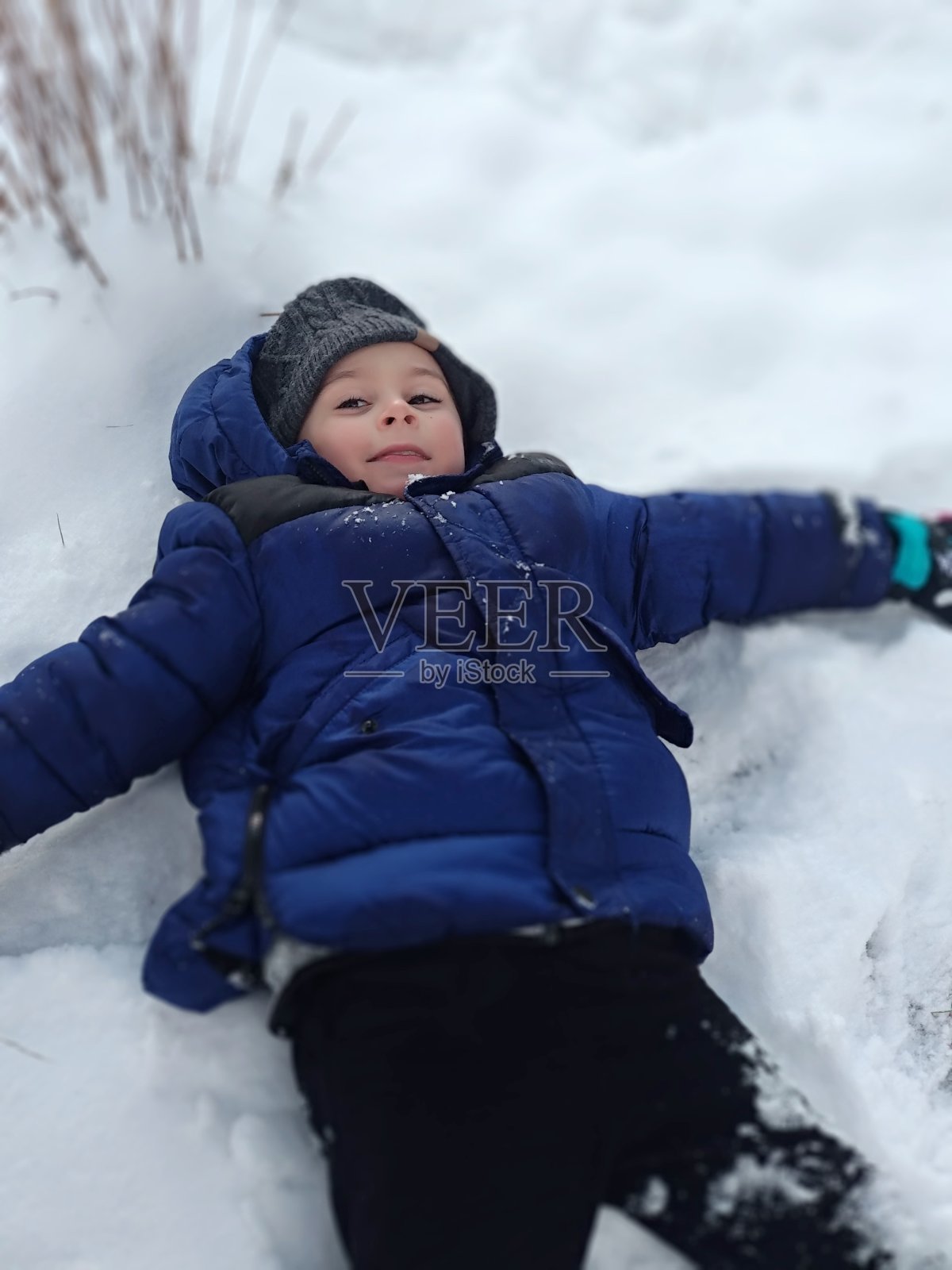 小男孩躺在雪地上照片摄影图片