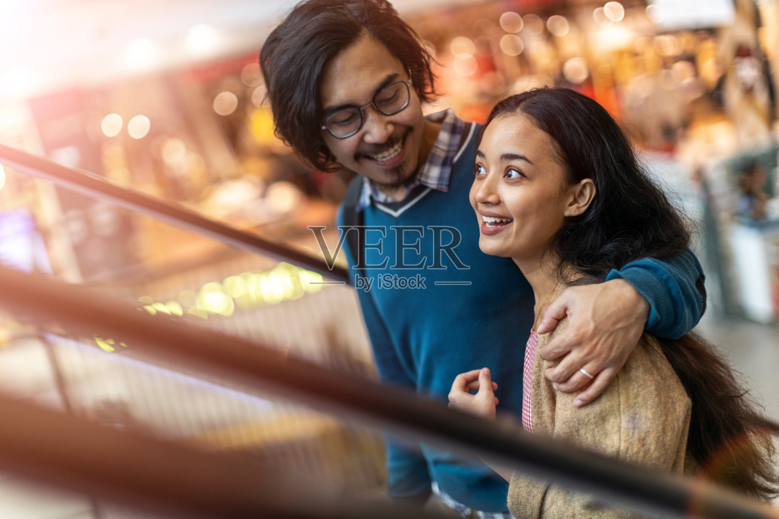一对快乐的年轻情侣在购物中心的自动扶梯上照片摄影图片