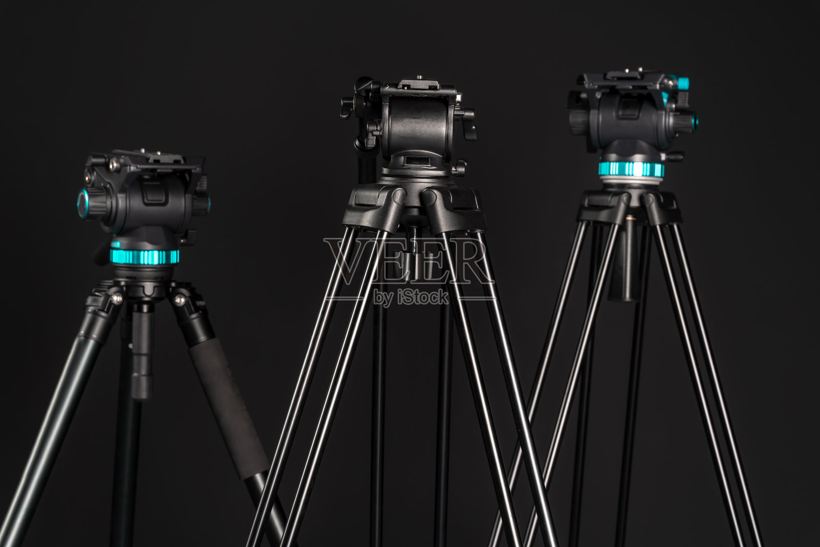 三个专业视频相机三脚架与相机头和释放板在黑色背景照片摄影图片