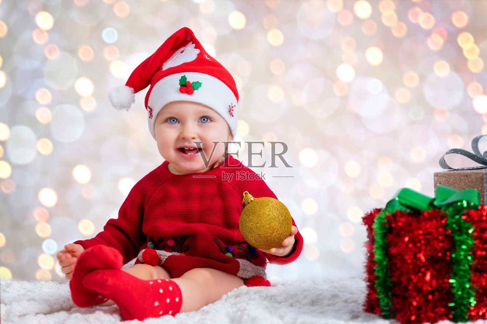 一个戴着圣诞帽的小女孩的肖像，手里拿着一个圣诞装饰品照片摄影图片