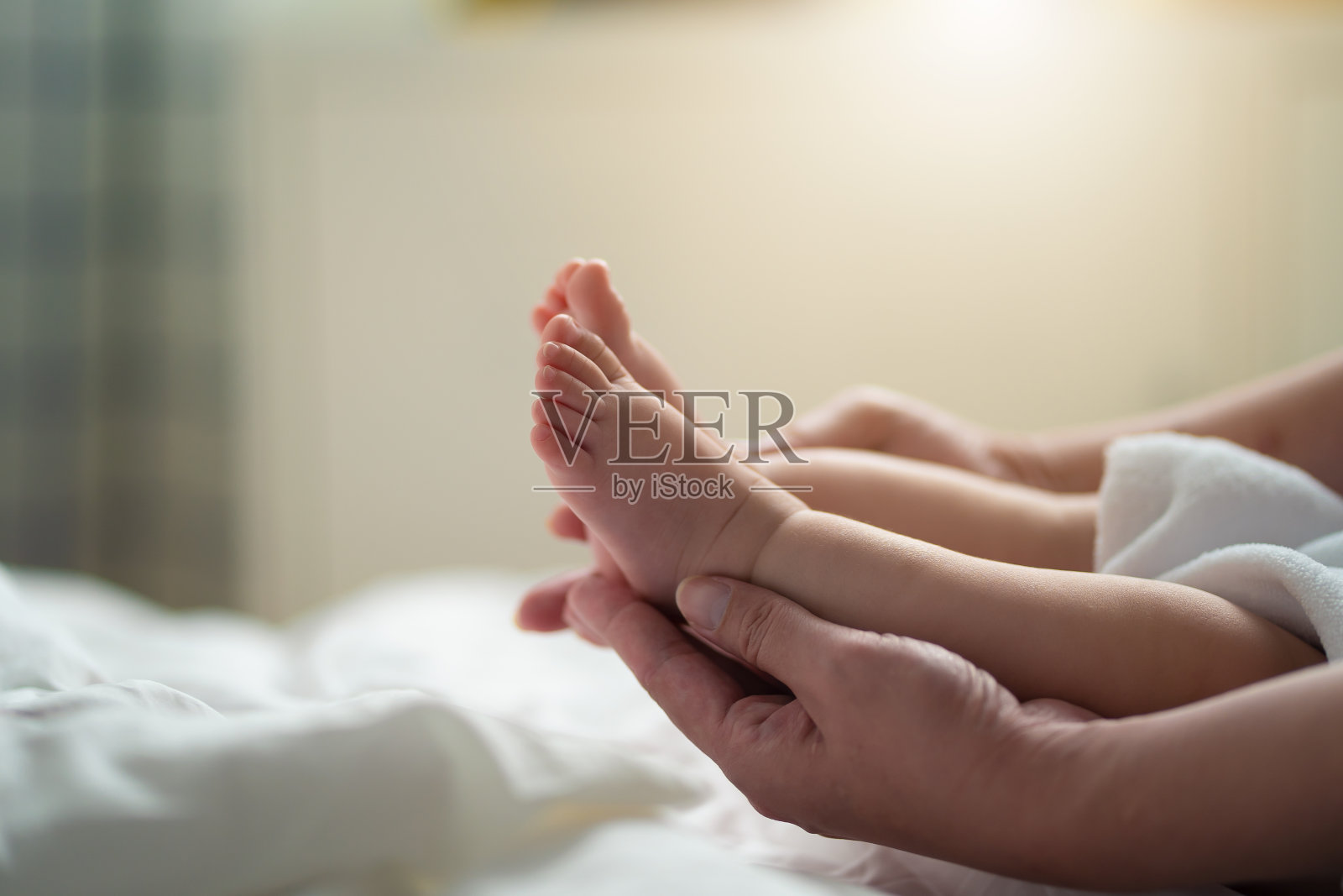 亚洲男婴的脚在她妈妈的手里。小新生儿的脚在女性的手从侧面近距离看到。美丽的母性概念形象。妈妈和宝宝，幸福的家庭理念。照片摄影图片