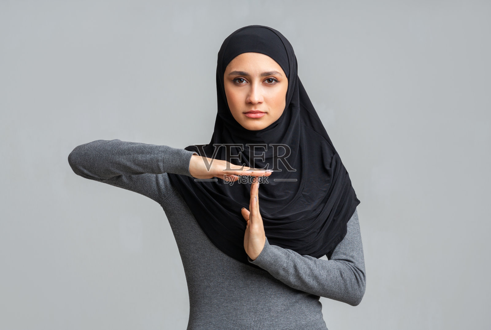 严肃的伊斯兰女孩做出暂停手势，示意暂停照片摄影图片
