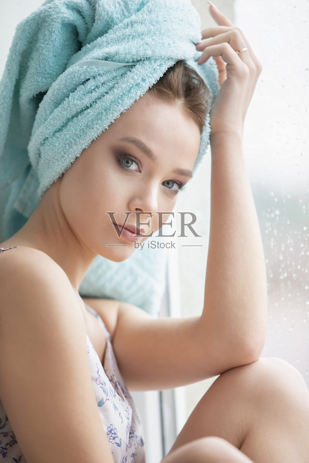 一个漂亮的女孩用毛巾洗完澡坐在窗边。照片摄影图片