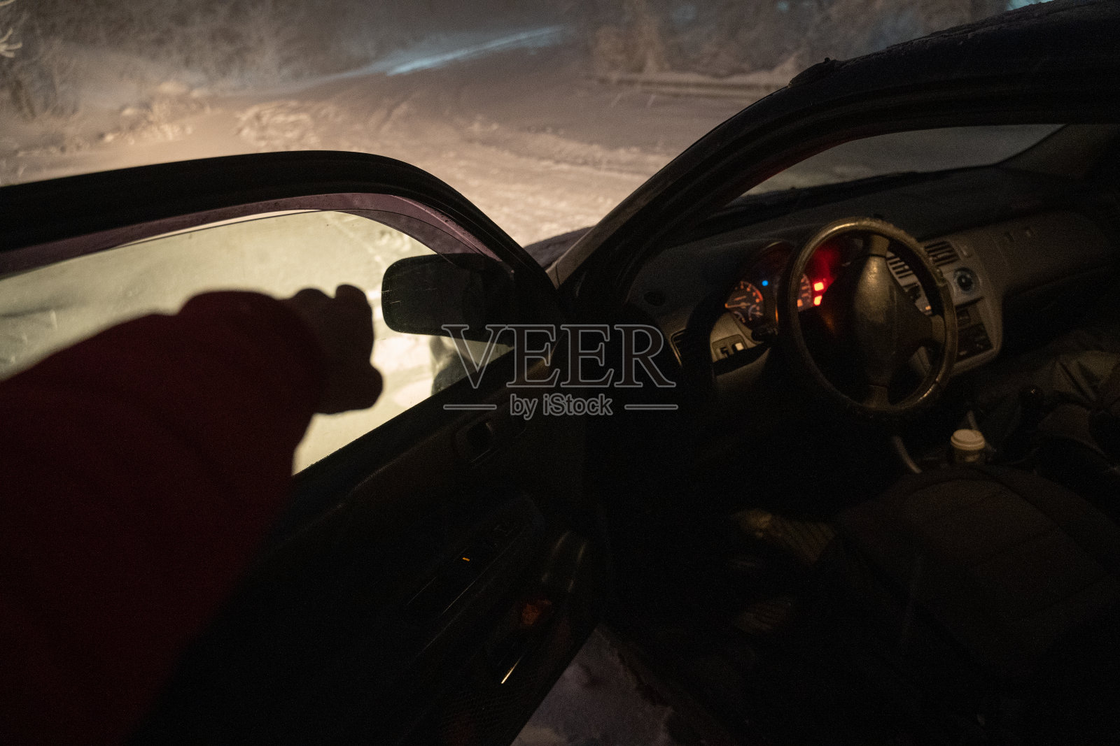 汽车观点。在雪夜里开车。汽车在路上抛锚了。在恶劣的天气下，汽车会在偏僻的地方抛锚。汽车保险。一个女人在路上。照片摄影图片