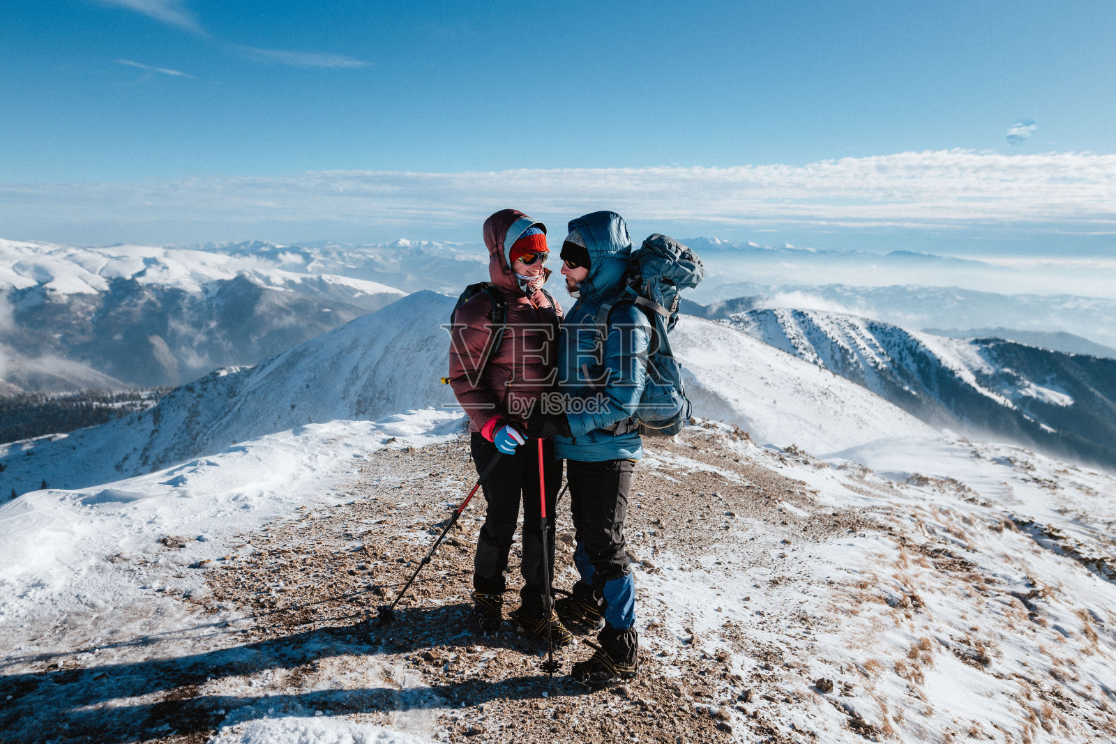 在冬季的群山中，一对登山者看着对方照片摄影图片