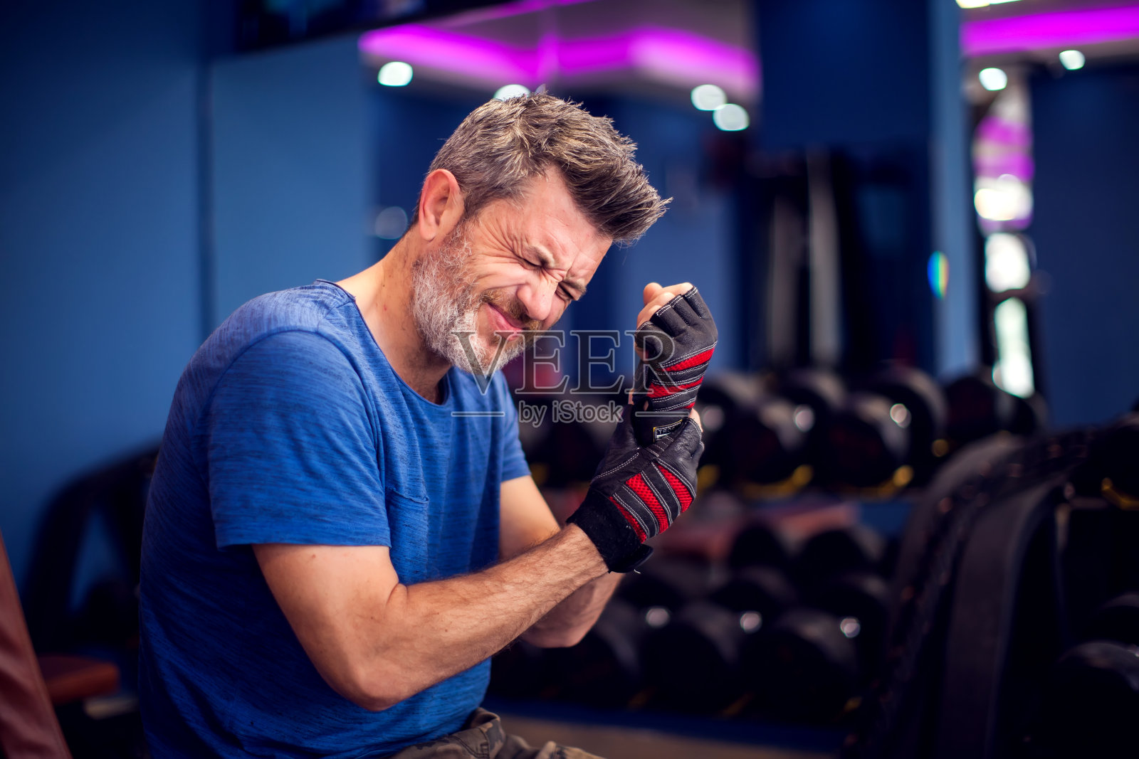 男人在健身房训练时感到手臂强烈疼痛。人，健身和保健的概念照片摄影图片