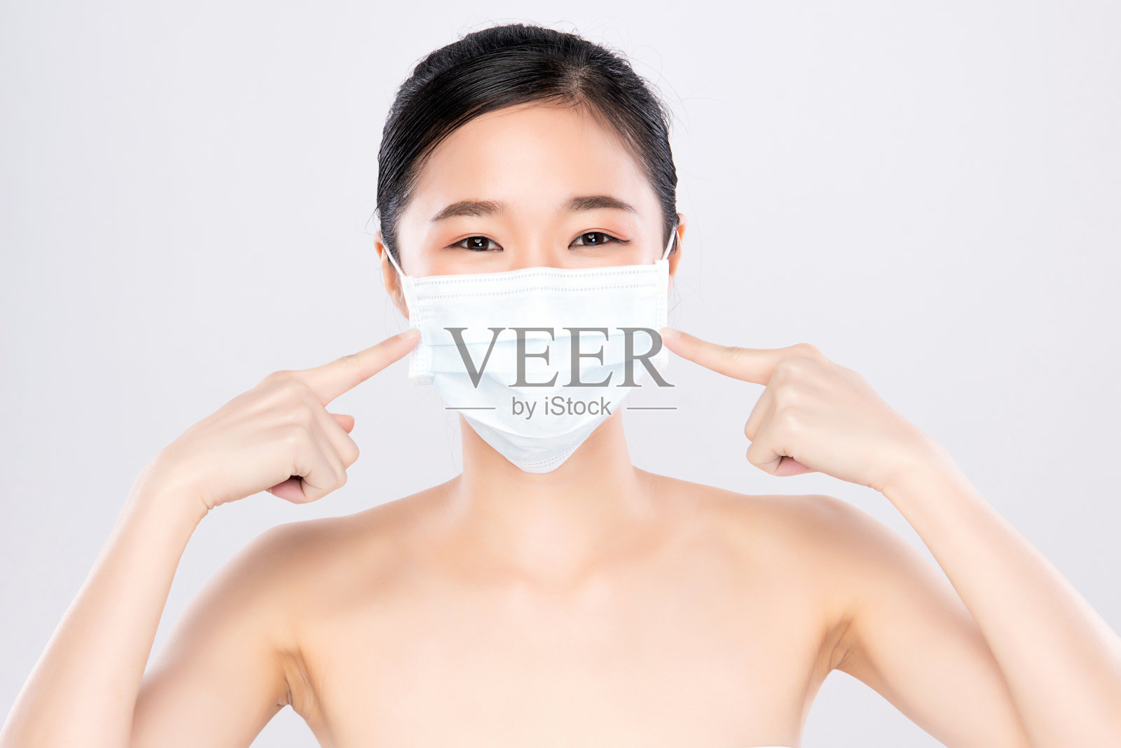 一名亚洲妇女戴着医用口罩，背景为白色照片摄影图片