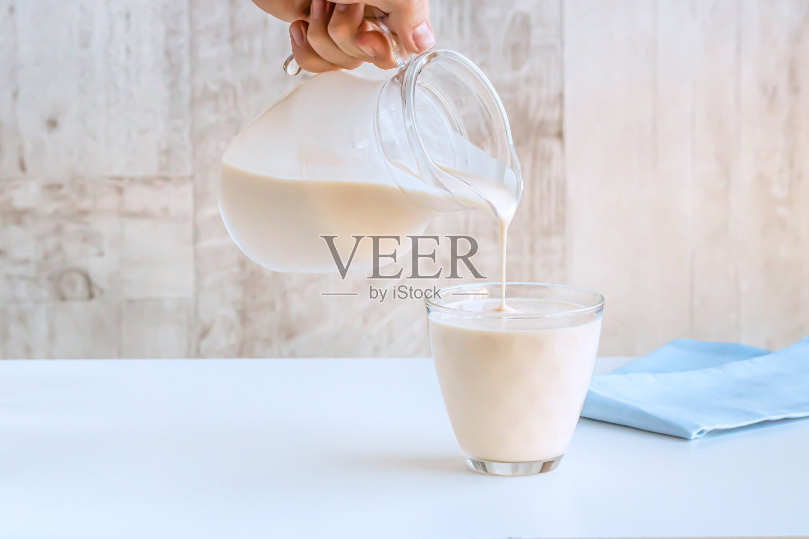 发酵的烘焙牛奶从罐子里倒进玻璃杯里。照片摄影图片