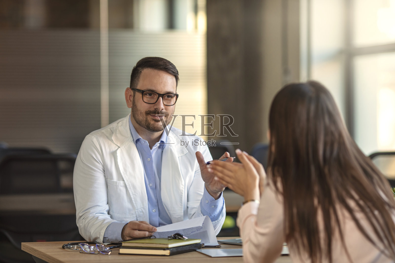 穿着白大褂的男医生正在咨询他的病人。照片摄影图片