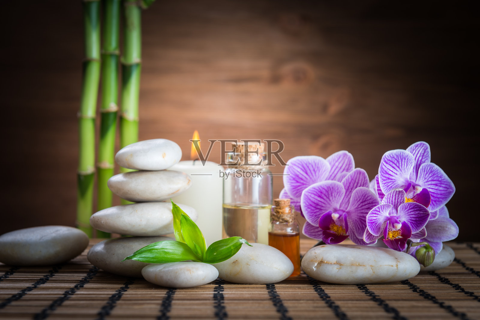 白色禅宗平衡石，兰花，竹植物和蜡烛在木桌上照片摄影图片