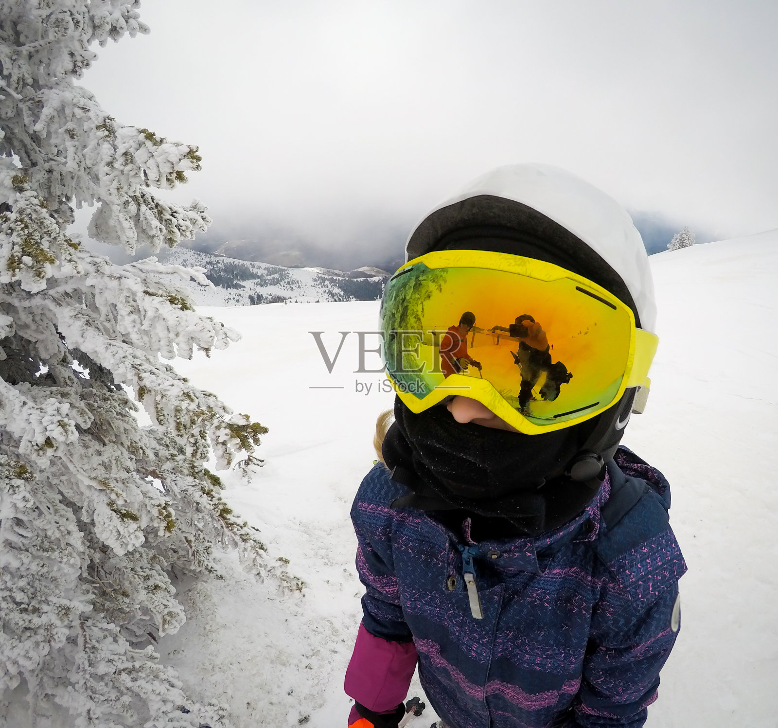 年轻的滑雪女孩在滑雪斜坡上的特写与大的黄色护目镜的反射。照片摄影图片