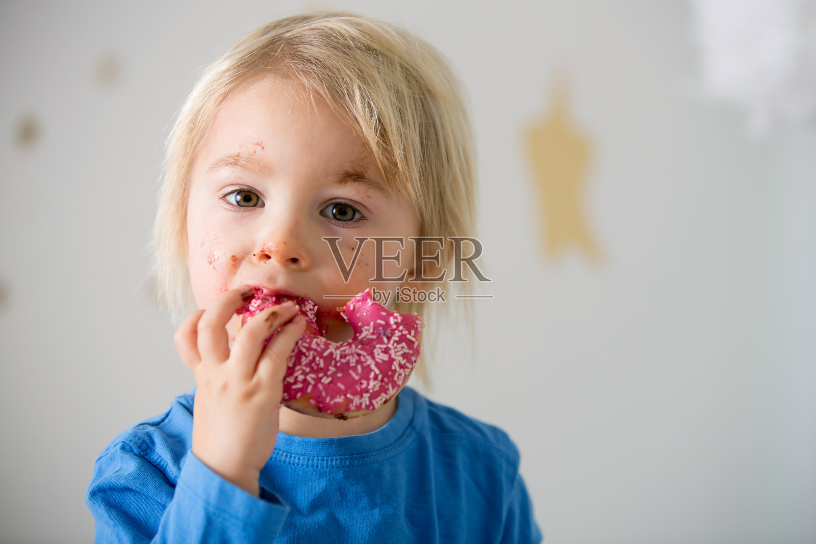 可爱的金发小孩，玩着吃着甜甜圈照片摄影图片
