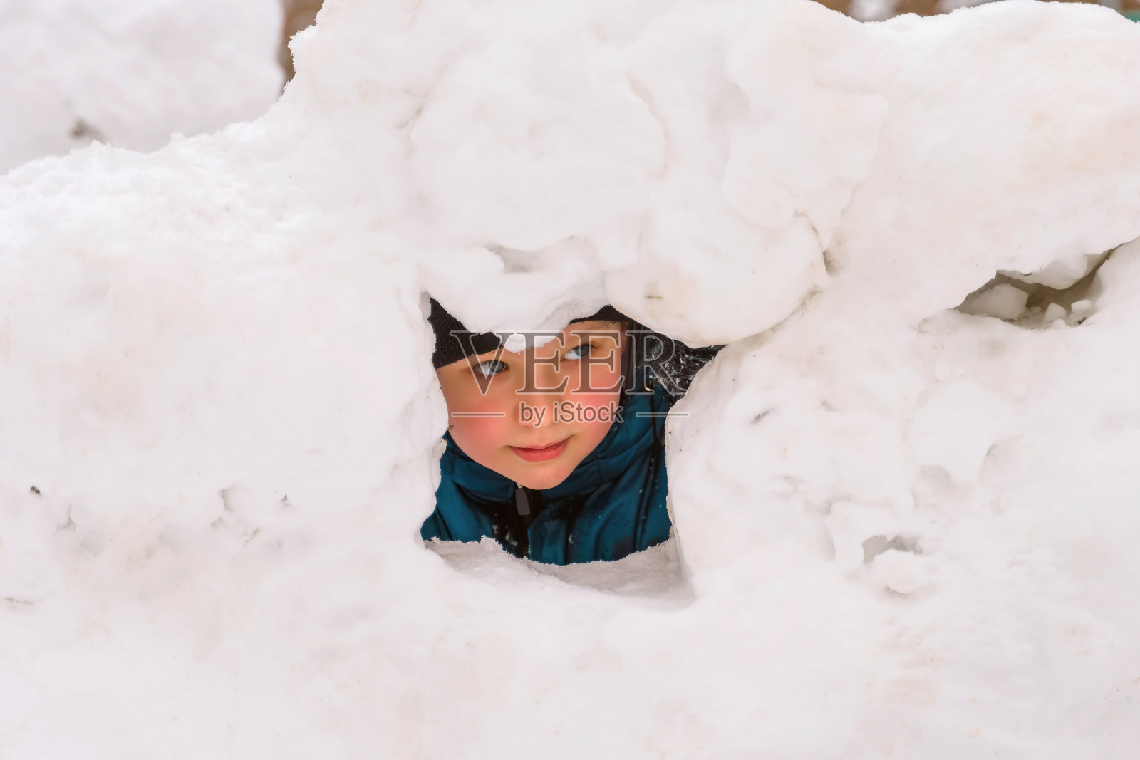 一个男孩的脸，向雪堡垒外看照片摄影图片