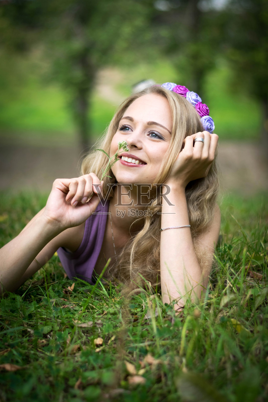 美丽的金发女孩躺在草地上笑着。照片摄影图片