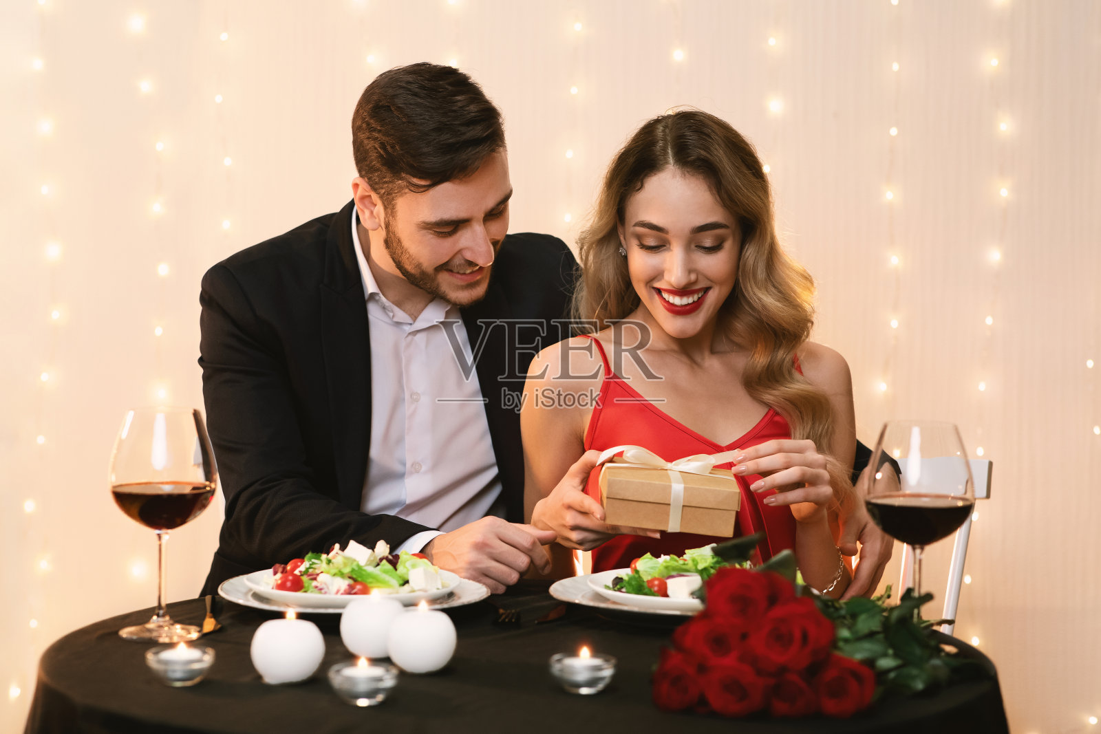 快乐的女人在餐厅打开男朋友送的礼物照片摄影图片