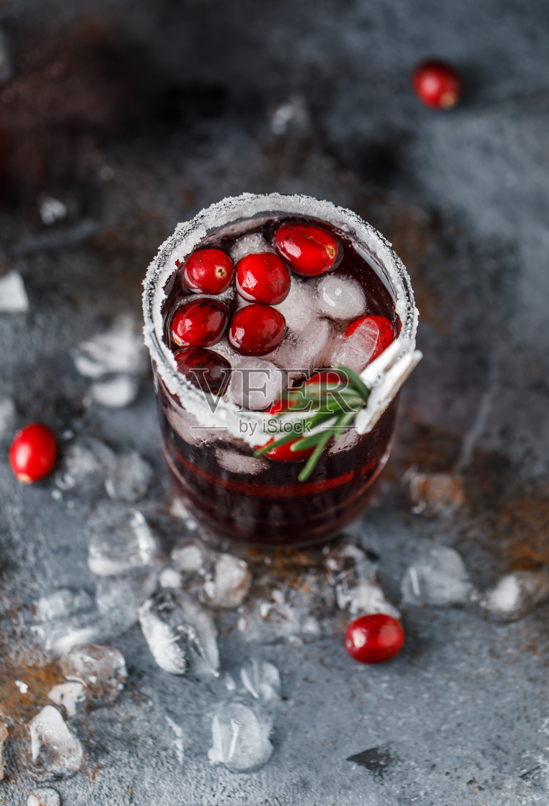 加冰的蔓越莓鸡尾酒。用糖和迷迭香装饰的玻璃杯装的圣诞蔓越莓饮料照片摄影图片