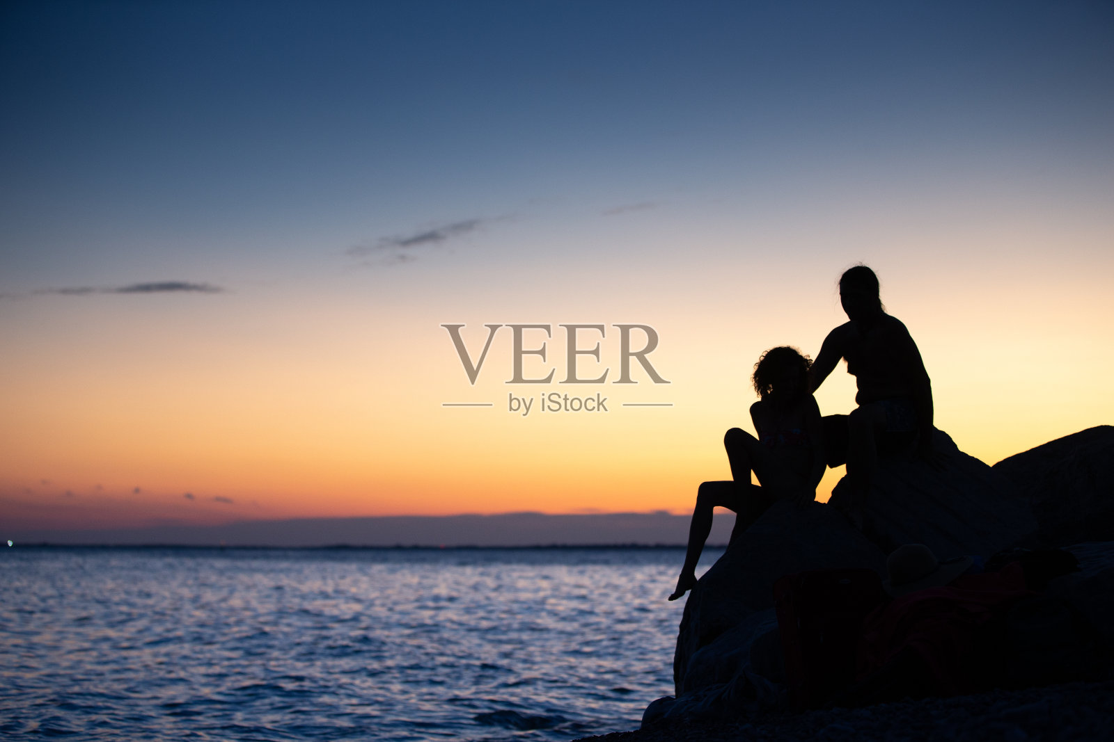 成年夫妇坐在海边和日落后放松剪影-股票照片照片摄影图片