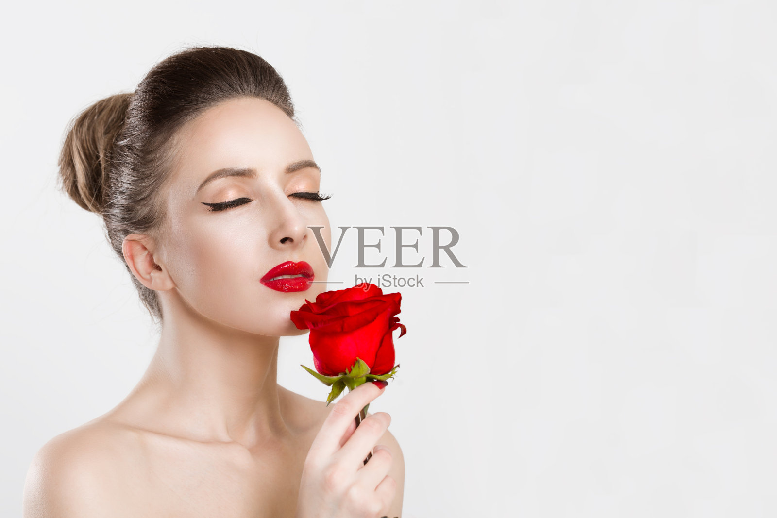 那女人用一朵红玫瑰把眼睛闭上了。孤立在白色照片摄影图片