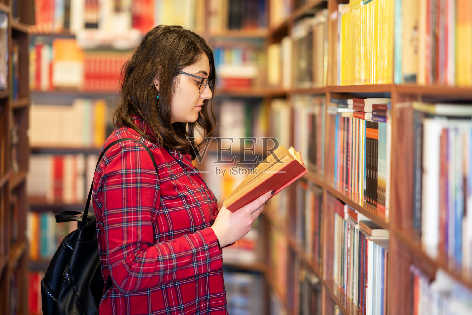 聪明的少女选择书籍，并从图书馆或书店中挑选。照片摄影图片