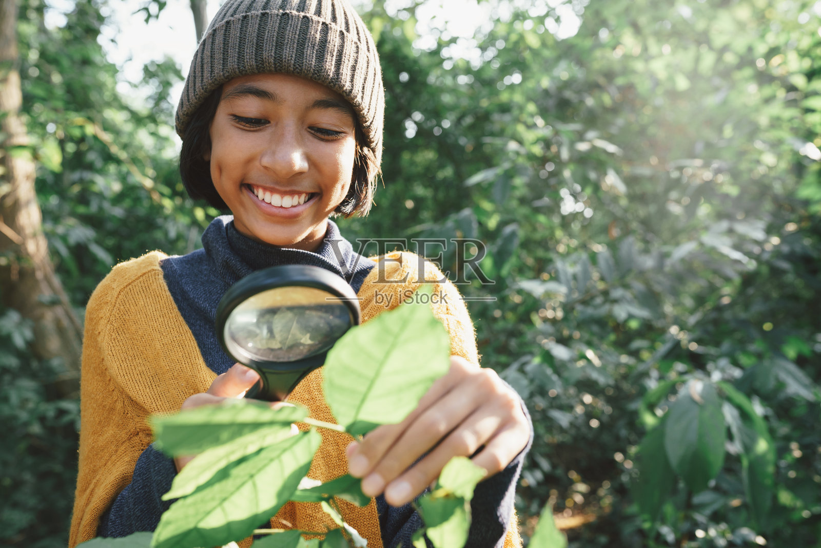 亚洲小女孩在清晨的阳光中，用放大镜和快乐的微笑探索着大自然照片摄影图片