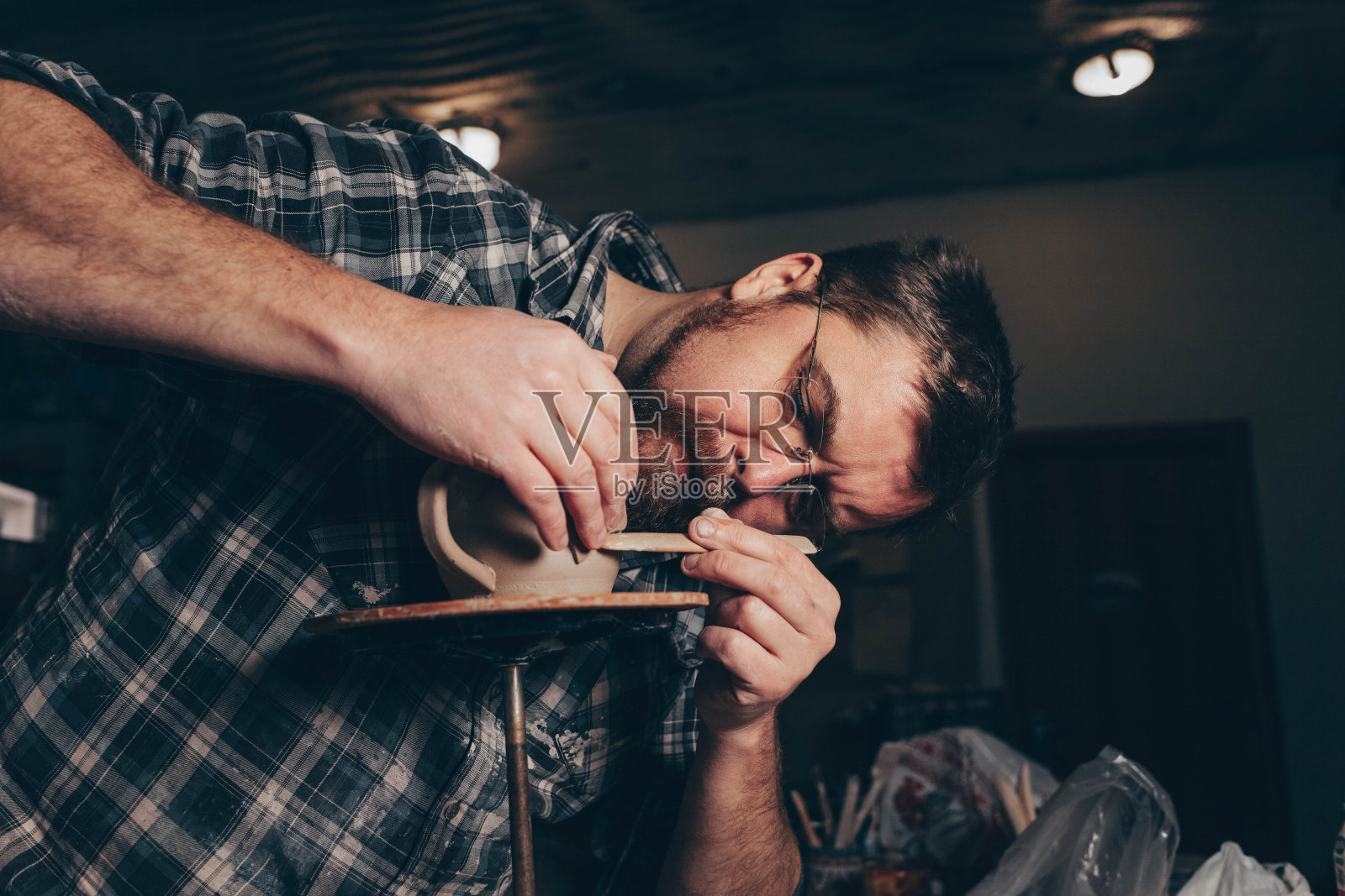 一名大胡子男子在一间陶器作坊里工作，专注于制作一个陶制杯子照片摄影图片