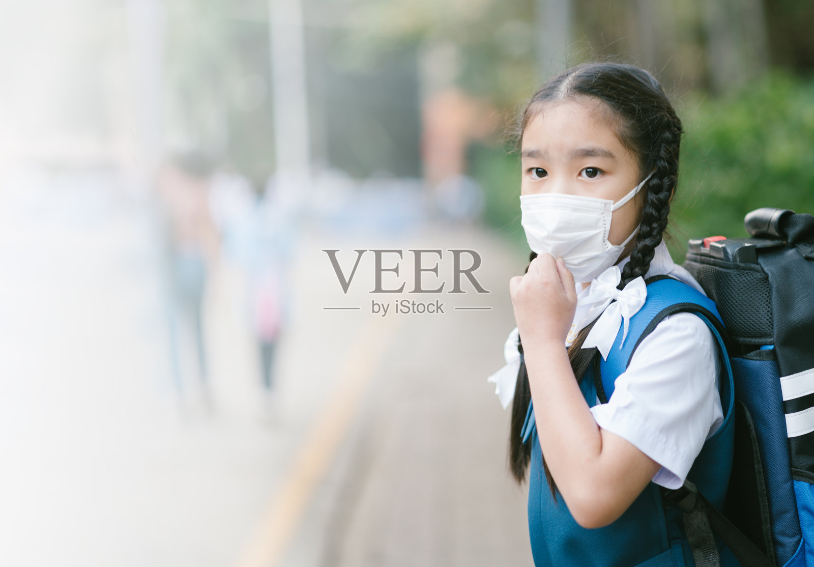 在泰国曼谷，一名女学生戴着口罩对抗空气烟雾污染照片摄影图片