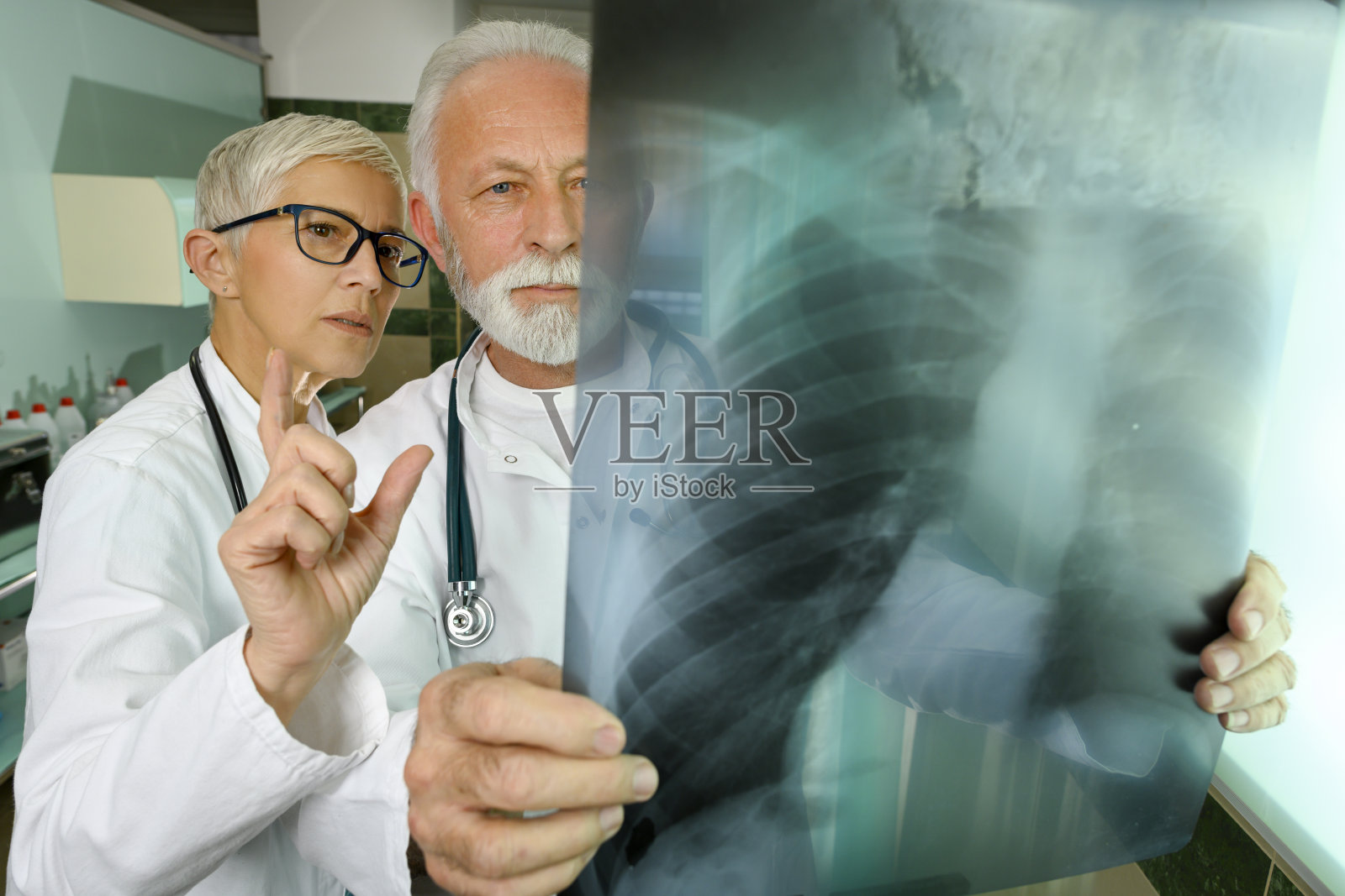 两位资深医疗从业者正在检查和评论一个病人的胸部x光图像照片摄影图片