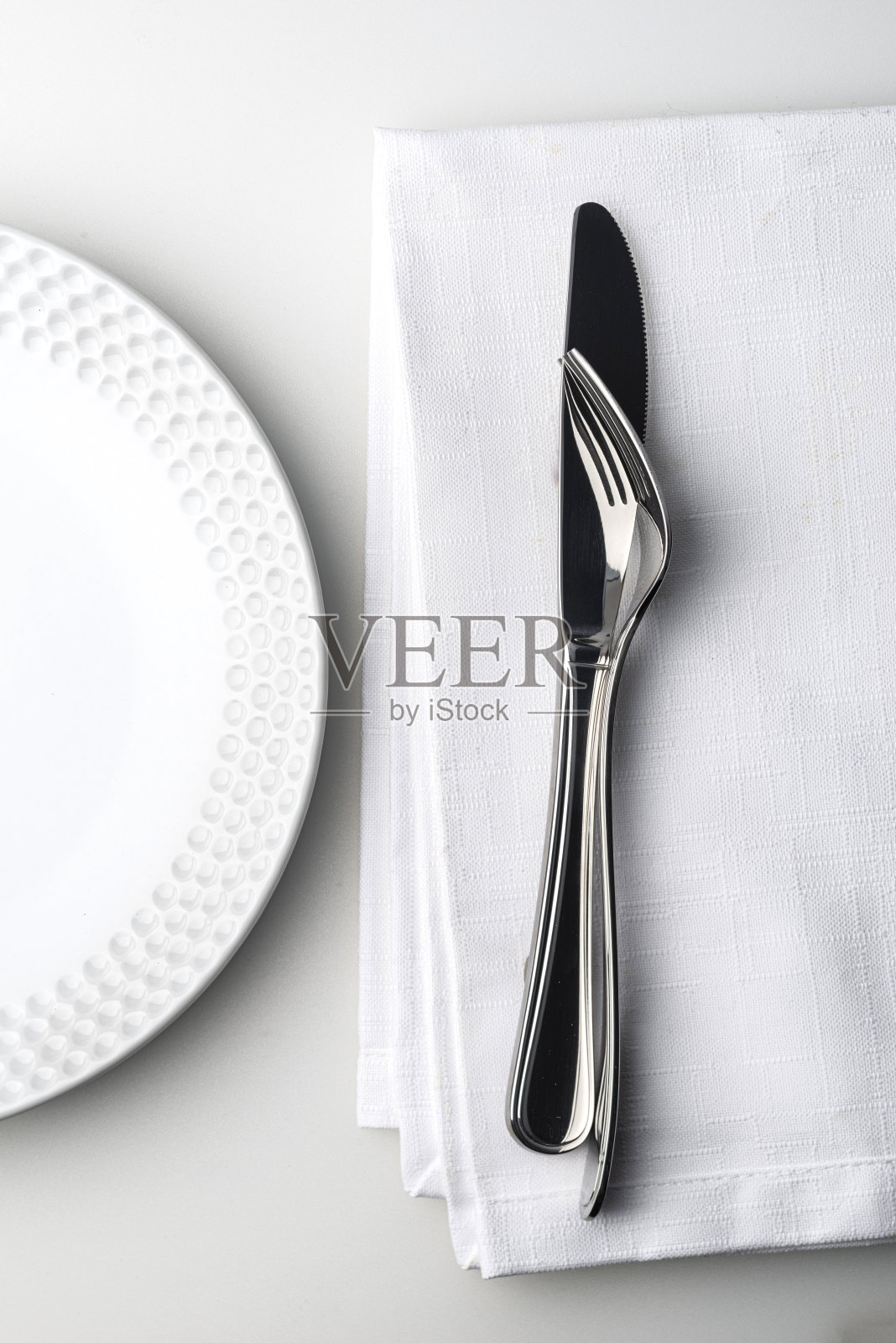 刀叉放在白色亚麻餐巾上。照片摄影图片