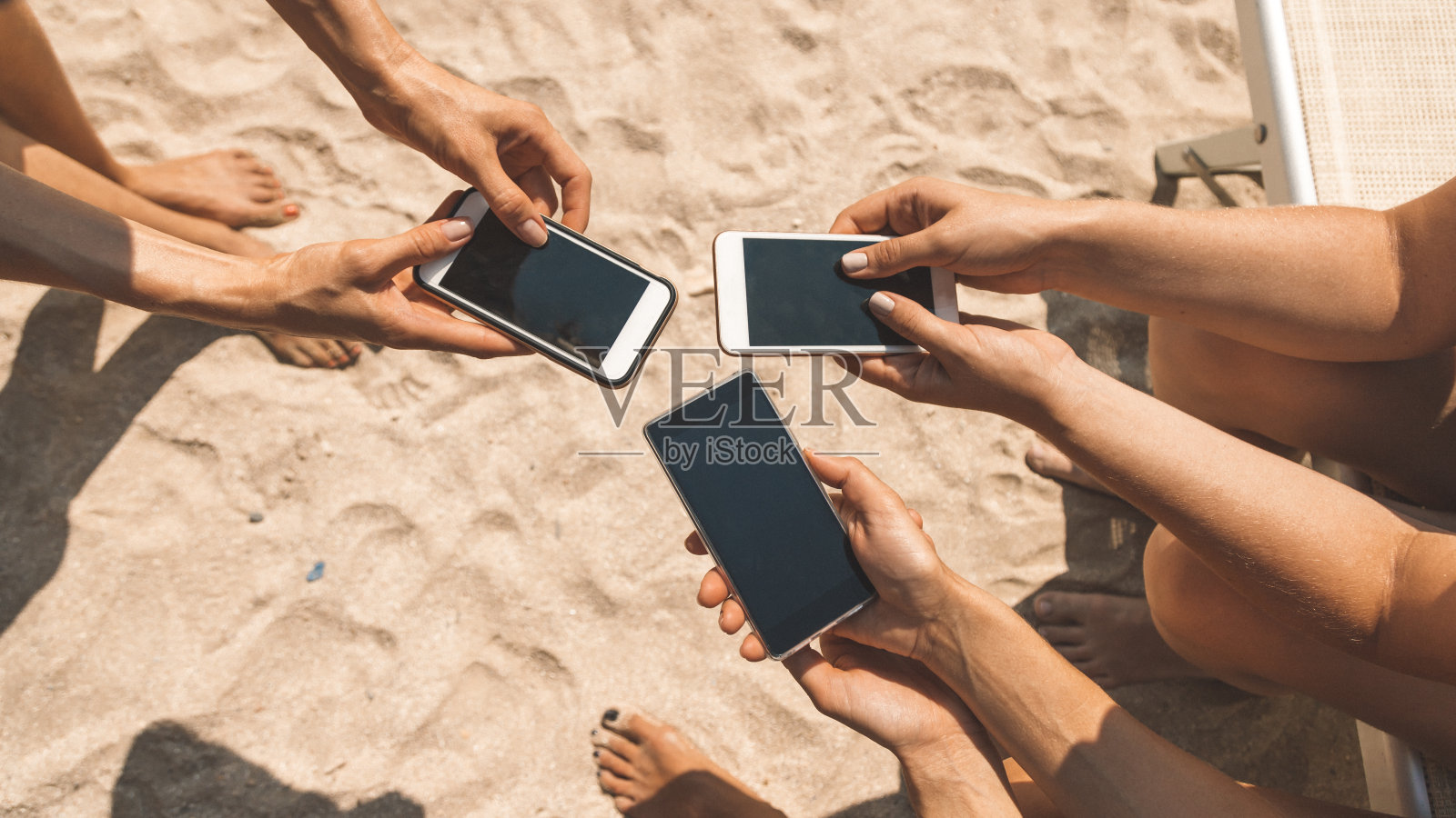 女性手握手机在社交网络上聊天或在海滩上网上购物的特写。强迫使用智能手机和网络成瘾的年轻人(千禧一代)的概念照片摄影图片