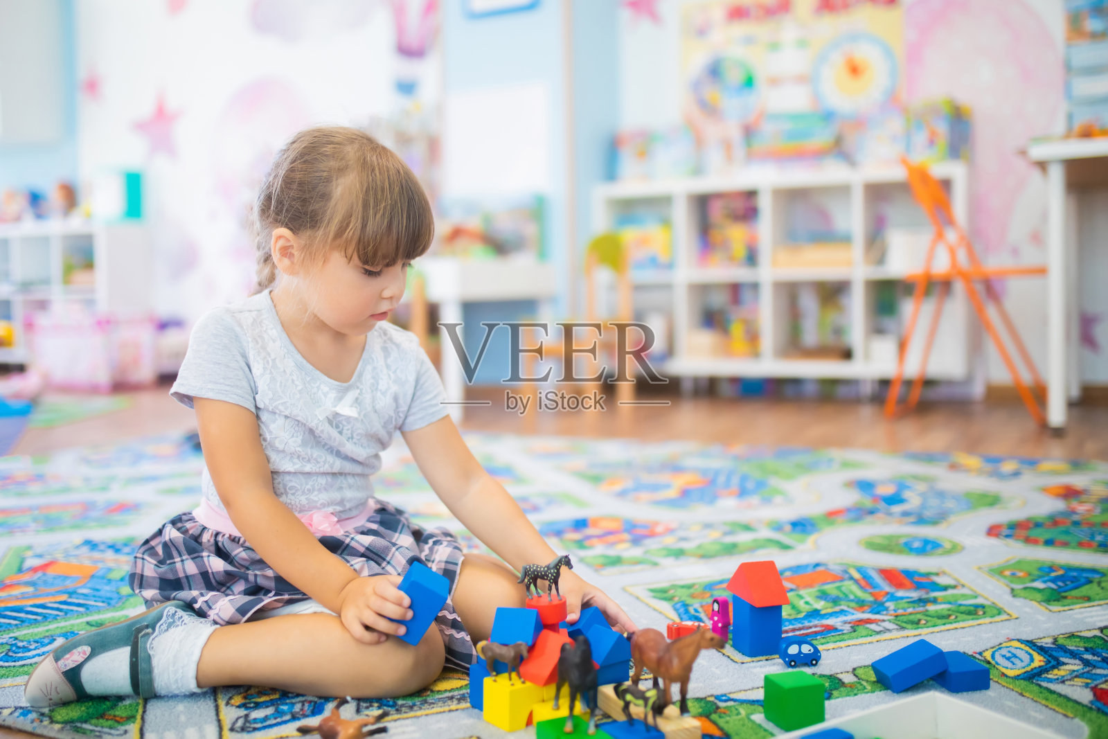 小女孩玩。孩子们有毛绒玩具。在家里或幼儿园的游戏室里，孩子们坐在儿童地毯上照片摄影图片
