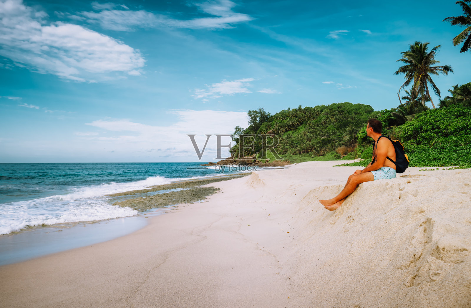 男游客坐在沙滩上享受热带海滩和海洋泻湖度假照片摄影图片