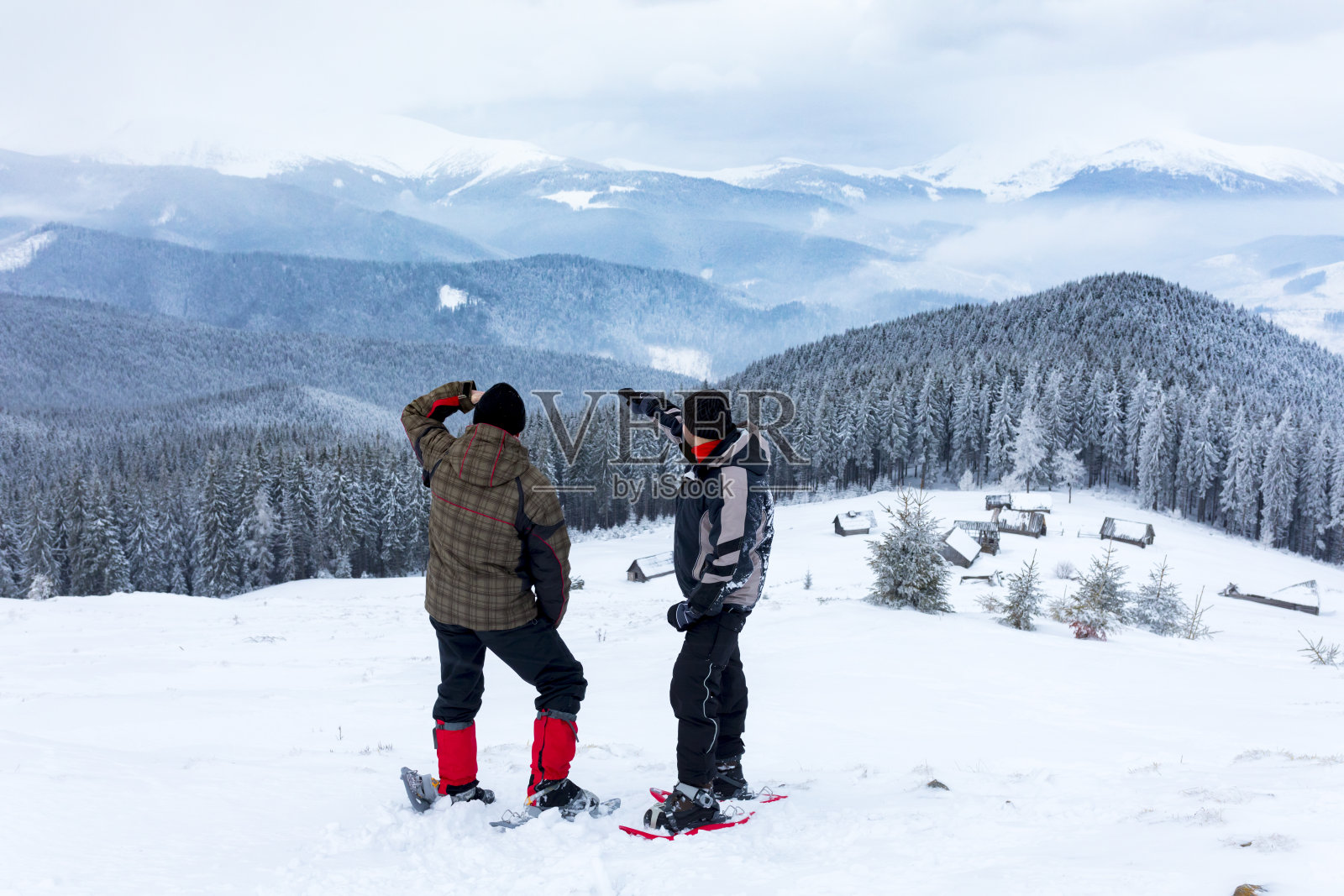两个穿雪鞋的男人看山。照片摄影图片