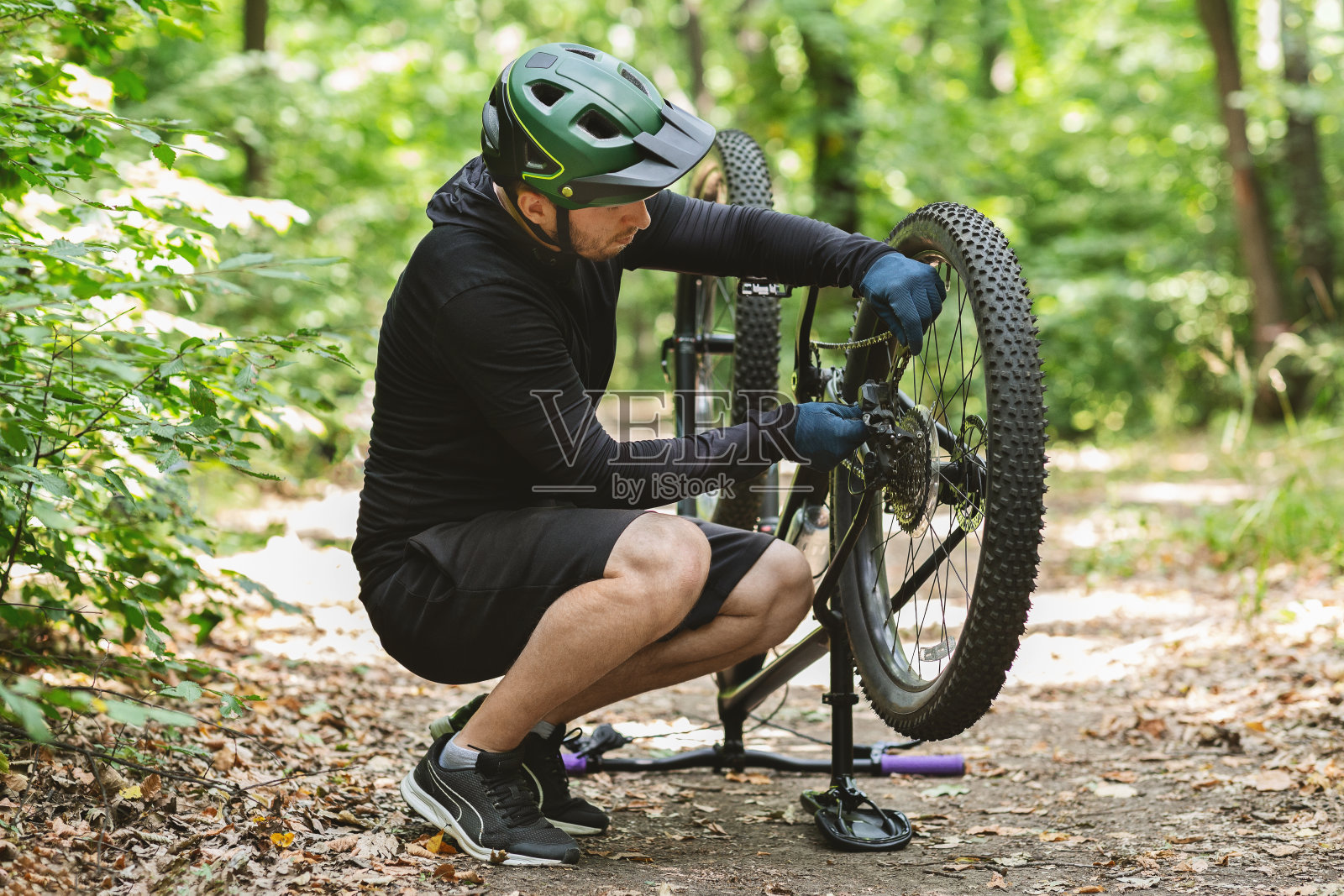 年轻的自行车手在森林里修理自行车链照片摄影图片