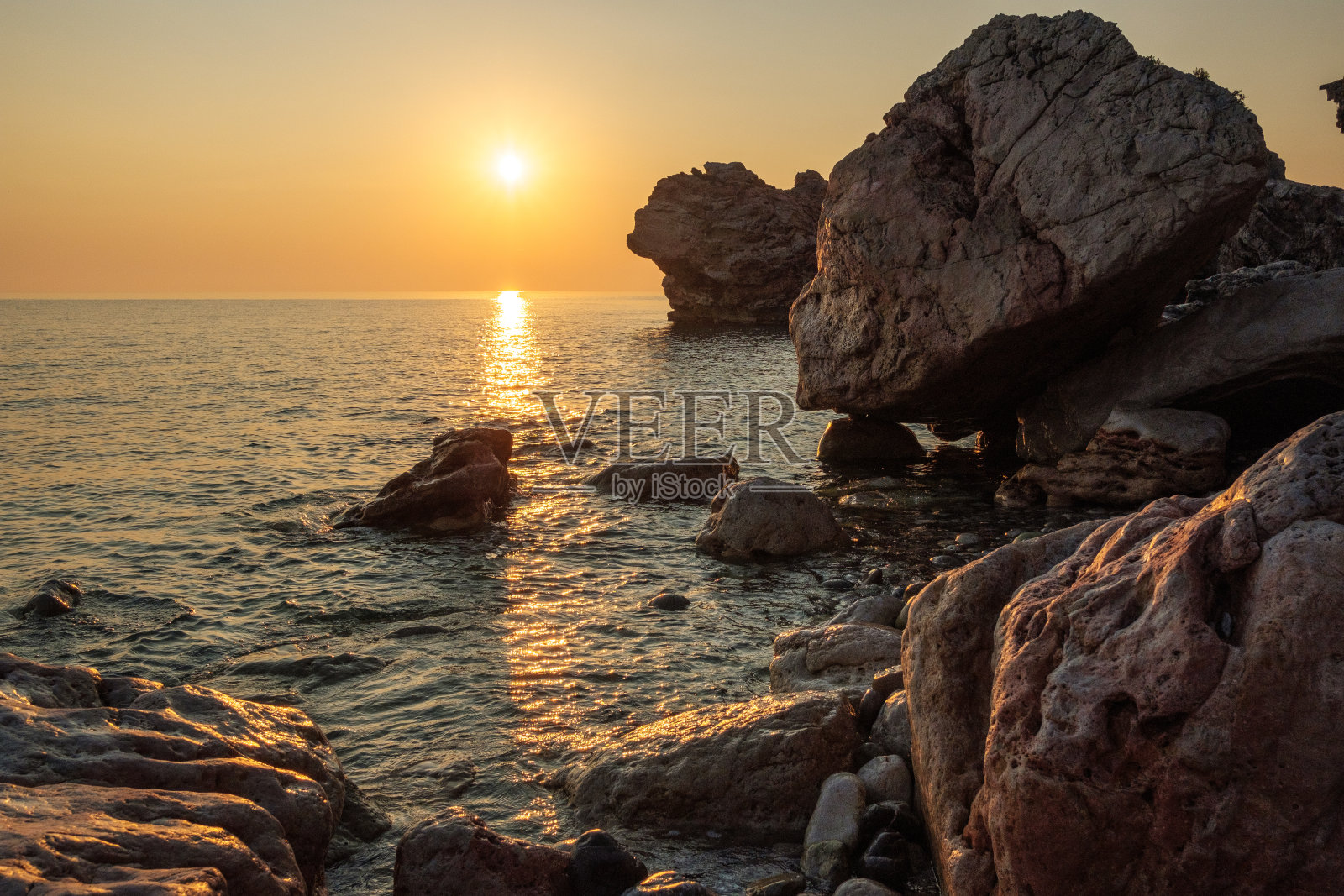 在多岩石的海岸上，日出在海面上的反射照片摄影图片