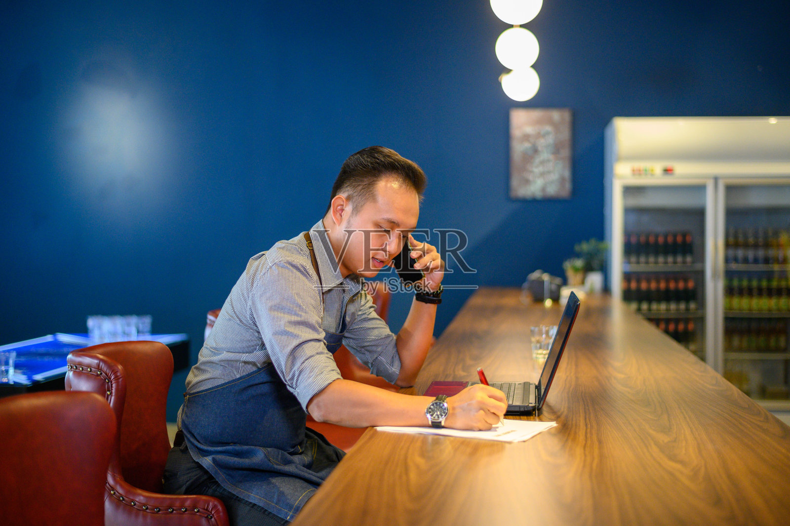 亚洲男子咖啡师穿围裙说话和接受订单从客户在咖啡馆照片摄影图片