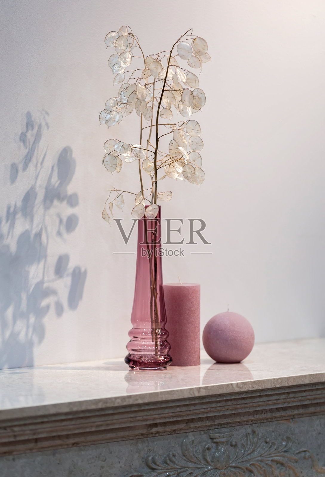 灰粉色的花瓶和一支蜡烛，壁炉上的装饰构图，花瓶里的月神花干花照片摄影图片