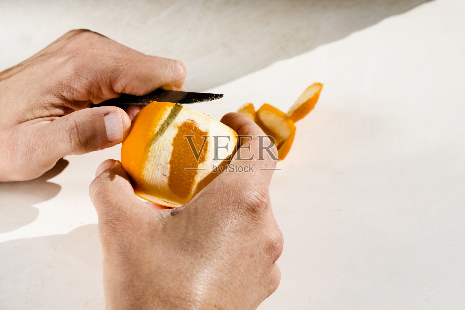 一个人在用刀剥橘子照片摄影图片